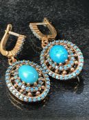 Pair of silver earrings with central panelled turquoise in a halo style