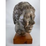 Metal sculpture of a persons head mounted on a wooden plinth