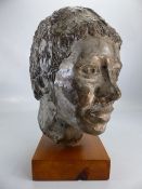 Metal sculpture of a persons head mounted on a wooden plinth