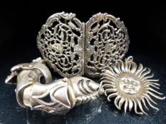 Three metal silver coloured items to include belt buckle, sun pendant and ring