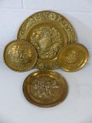 Four brass embossed plates or platters