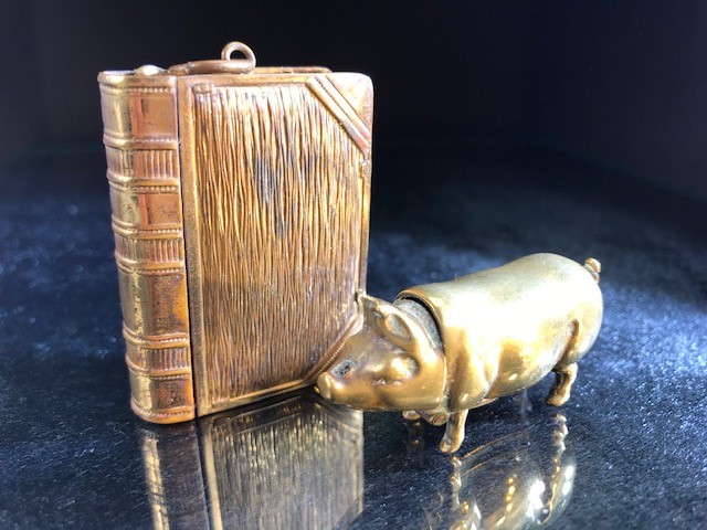 Two brass vesta cases, one in the form of a pig, the other a book