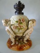 German porcelain table lamp, modelled on a flower encrusted basket supported by three cherubs,