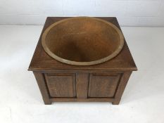 Large metal couldron in panelled wooden stand.