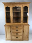 Pine dresser with four drawers with brass handles, two cupboards and shelves over