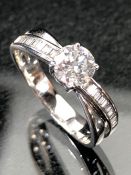 18ct white gold ring with central brilliant cut stone and cross over diamond shoulders