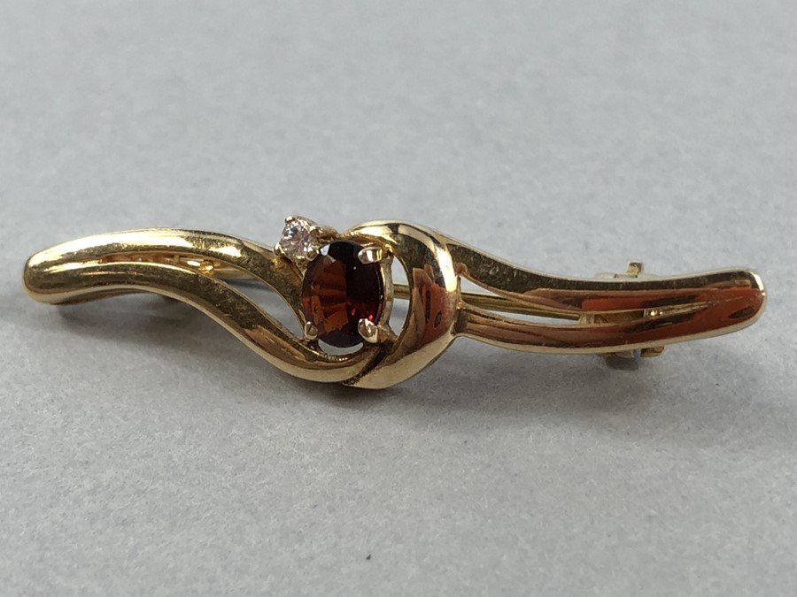 9ct Gold marked 375 Brooch set with central faceted Garnet and a single Diamond