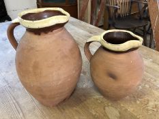 Two rustic terracotta jugs with unglazed bodies and glazed two-tone rims