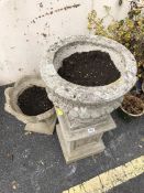 Two concrete Urns one on plinth