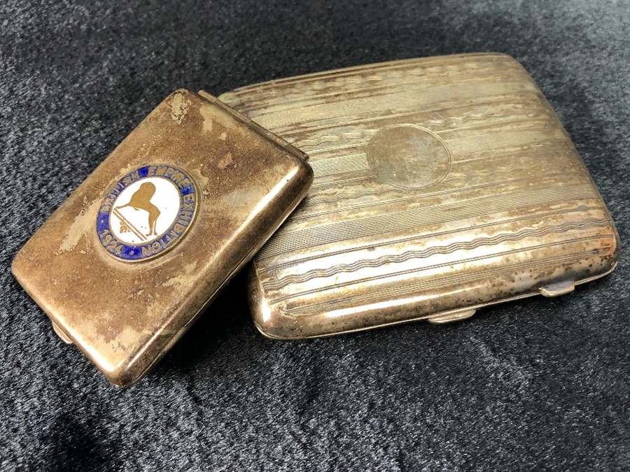 Two Silver coloured cigarette boxes one with enamel badge which reads "British Empire Exhibition