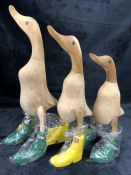 Three ornamental carved wooden ducks in 'Hunter' style wellies, the tallest approx 35cm in height