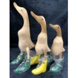 Three ornamental carved wooden ducks in 'Hunter' style wellies, the tallest approx 35cm in height