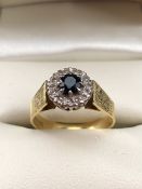 18ct Hold fully hallmarked daisy style ring set with central stone (possibly a dark sapphire) and