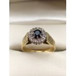 18ct Hold fully hallmarked daisy style ring set with central stone (possibly a dark sapphire) and