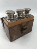 Brown leather travel case containing three glass medicine/ scent bottles with silver coloured