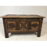 Dark wood coffer with panelled lid and carved floral design to front, approx 105cm x 51cm x 58cm