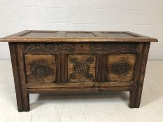 Dark wood coffer with panelled lid and carved floral design to front, approx 105cm x 51cm x 58cm