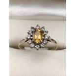 A CITRINE AND DIAMOND DAISY/CLUSTER RING the oval-shaped citrine is set within a surround of