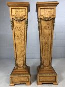 A pair of ornate walnut pedestals, of tapered form, with black marble tops and ormolu mounts, on a