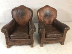 Pair of vintage brown leather armchairs/club chairs with embossed emblem to back, studwork