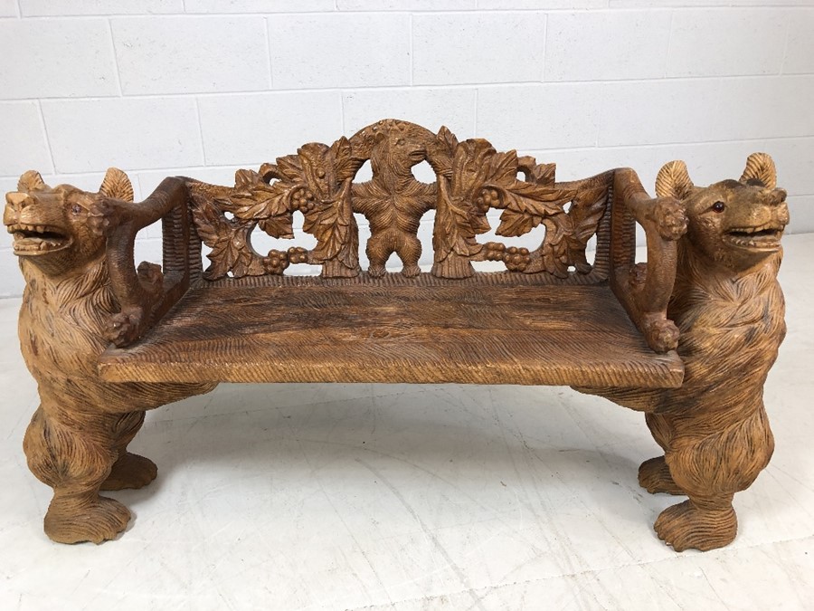 A Black forest style low bench, with two bears flanking a carved back and solid seat, approx 120cm x