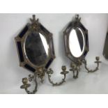Pair of Continental metalwork mirrors and candle sconces in the Rococo style, the oval bevel edged
