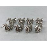 Eight silver coloured heavy placeholder card holders in the shape of ducks in a John Somers Box