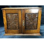 Edwardian smokers cabinet with carved decoration, two internal drawers and two pipes in racks,