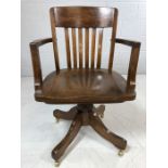 Wooden captain's chair on brass castors with slatted back