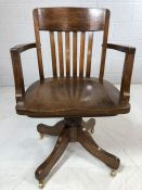 Wooden captain's chair on brass castors with slatted back