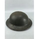 Military tin Brodie helmet with original webbing and black liner