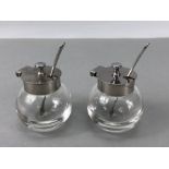 Pair of circular glass salts with silver coloured lids & Matching spoons marked "T 18 - 8"