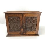 Oak smokers cabinet with carved detailing to doors and hinged lid revealing ceramic tobacco jar