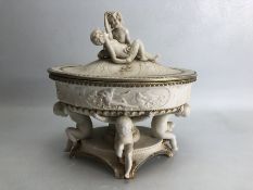 Porcelain lidded centrepiece with cherub detail to top and legs, approx 25cm in width and 23cm in