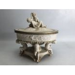 Porcelain lidded centrepiece with cherub detail to top and legs, approx 25cm in width and 23cm in