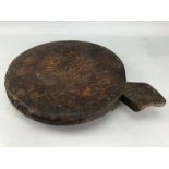 Large rustic wooden chopping board, approx 30cm in diameter, on three feet with handle to side