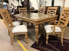 Light wood glass-topped extending dining table with carved detailing and six chairs with upholstered