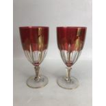Pair of red bohemian-style glass goblets with gold rims, approx 18.5cm in height