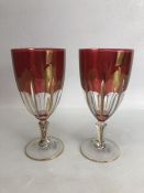 Pair of red bohemian-style glass goblets with gold rims, approx 18.5cm in height