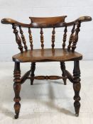 Smokers bow / elbow chair with spindled back, turned legs and castors to front, approx width 66 cm