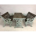 Wooden garden table and two benches with green painted cast iron ends and table base, benches approx