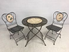 Metal latticework bistro table with inlaid decorated panels with two matching chairs