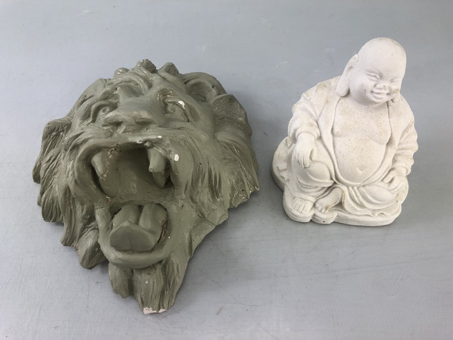 Plaster cast of a lions head painted green and a small seated buddha statue