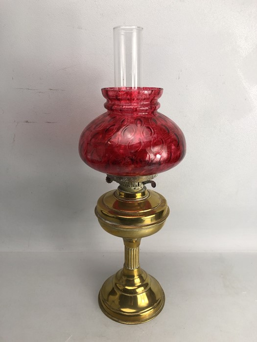 Brass based oil lamp with chimney and cranberry shade