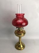 Brass based oil lamp with chimney and cranberry shade