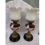 Pair of table lamps on circular ebonised and brass plinths,