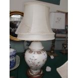 Cream based porcelain floral patterned table lamp on circular wooden plinth with cream parchment