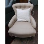 Low button backed armchair on castors, the padded arms,