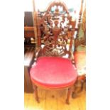 Smaller heavily carved back occasional chair on tapering turned feet on casters,