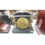 Decorative circular brass faced mantelclock in decorative black marble case